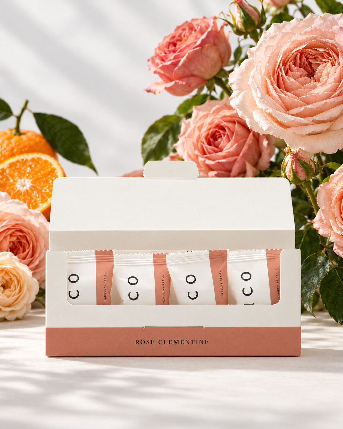 Elico handtvål refills 4-pack Ros & clementin, öppen kartong med fyra refills framför rosor och clementiner